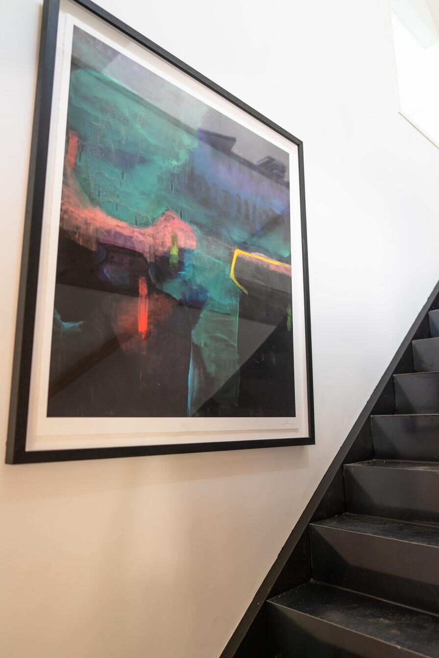 A framed abstract work on paper hanging beside the gallery's staircase